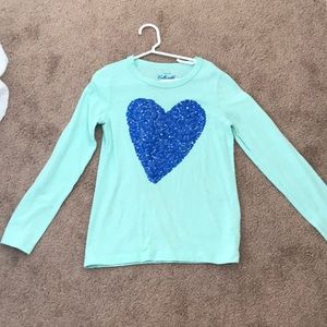 A turquoise girls shirt with a blue heart on front
